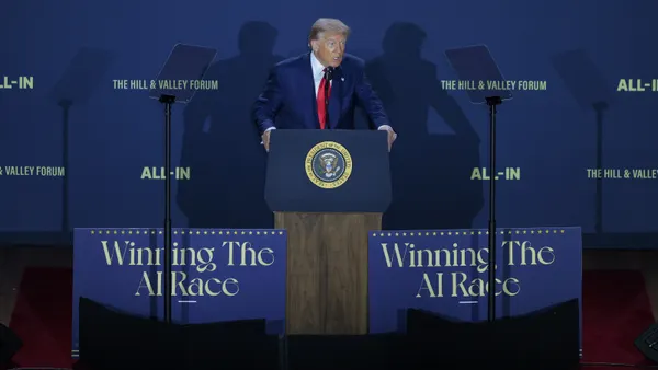 A man stands at a lectern near signs that read "Winning the AI race"