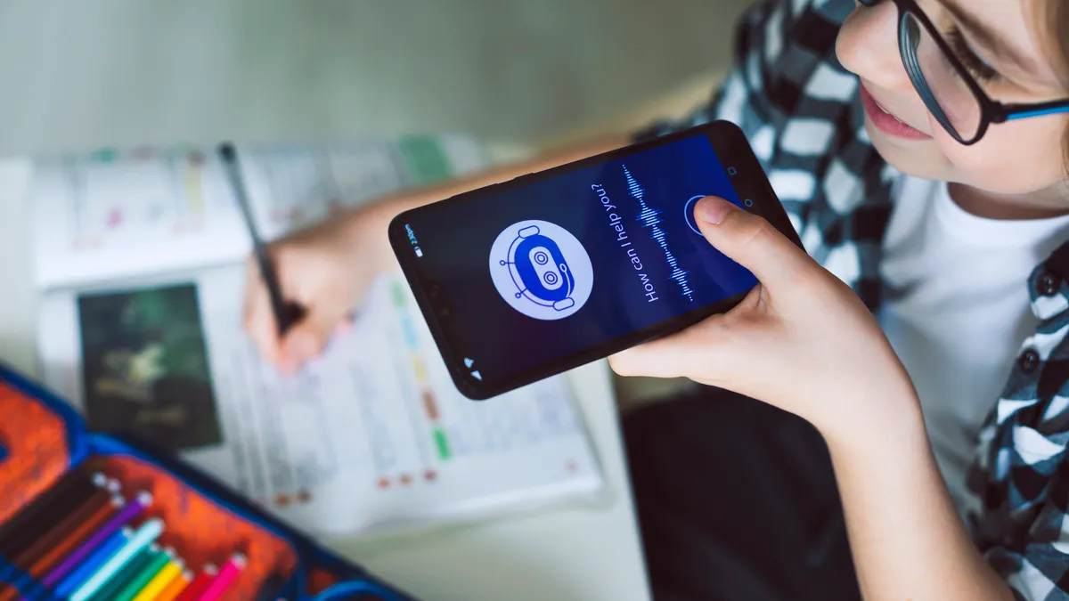 A young student speaks to an AI chatbot on their phone with "How can I help you?" written on the screen.