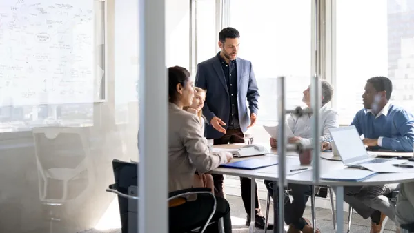 Latin American businessman talking to a group of coworkers in a business meeting at the office