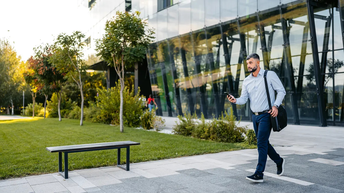 A man leaves an office while checking his phone.