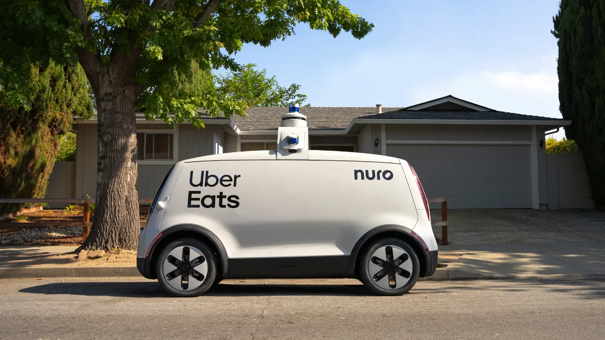 An image of a white autonomous vehicle in front of a house.