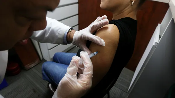A doctor gives a vaccine shot to an adult.
