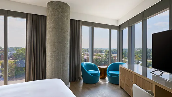 Two blue chairs in the corner of a hotel room.