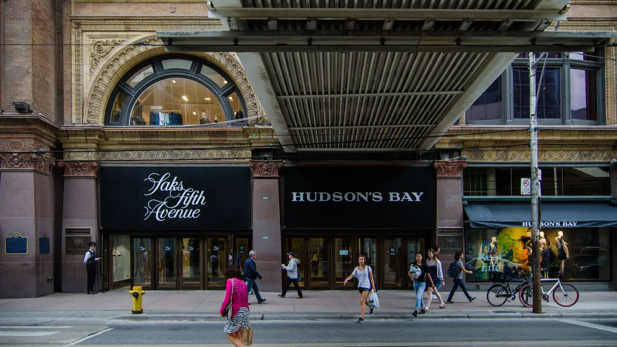 People walk around in front of Saks Fifth Avenue and Hudson's Bay department stores.