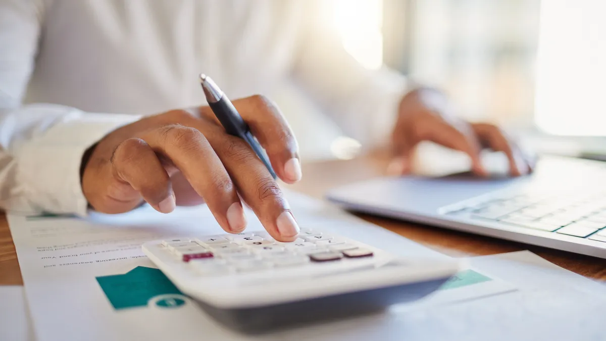 Close-up of a person on a computer and calculator.