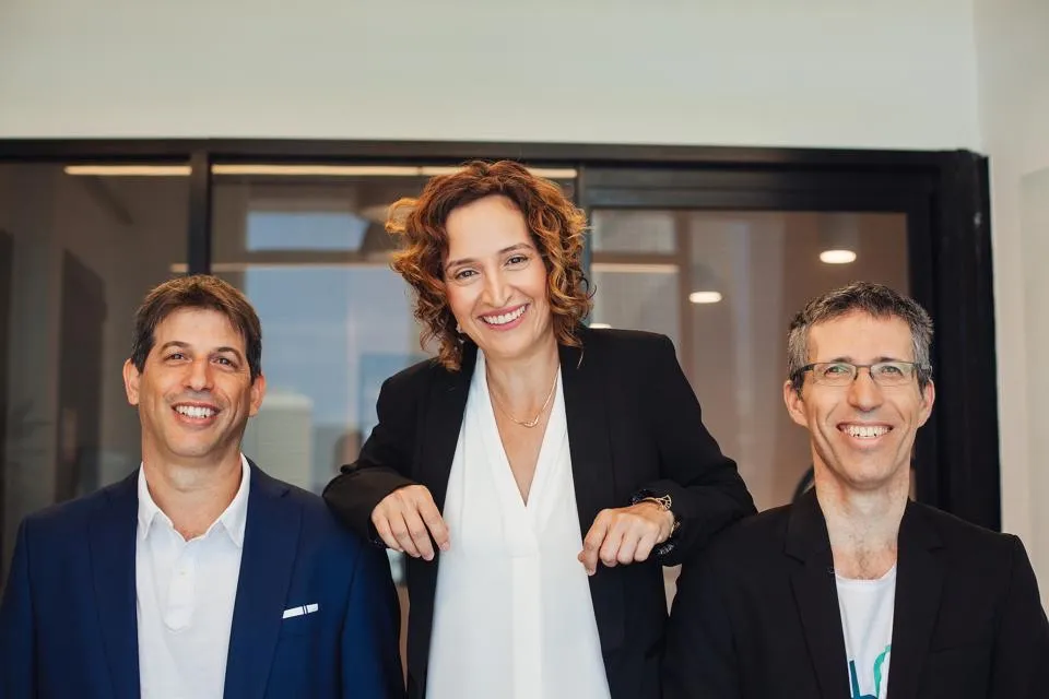 Two men sitting and a woman standing between them.