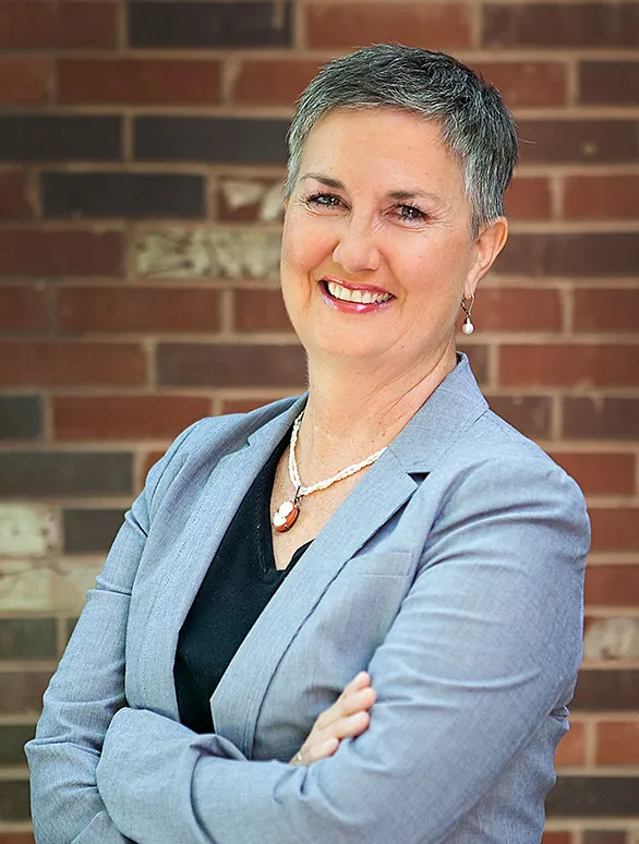 Portrait of a woman with short silver hair and a blue blazer.