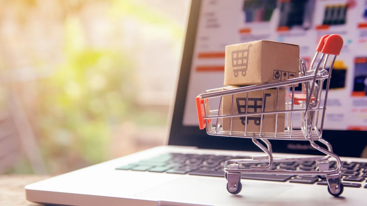 Parcel or Paper cartons with a shopping cart logo in a trolley on a laptop keyboard.