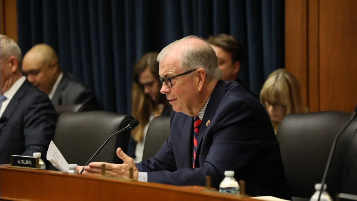 Michigan representative Tim Walberg sits behind a lectern as he speaks into a microphone during a congressional session