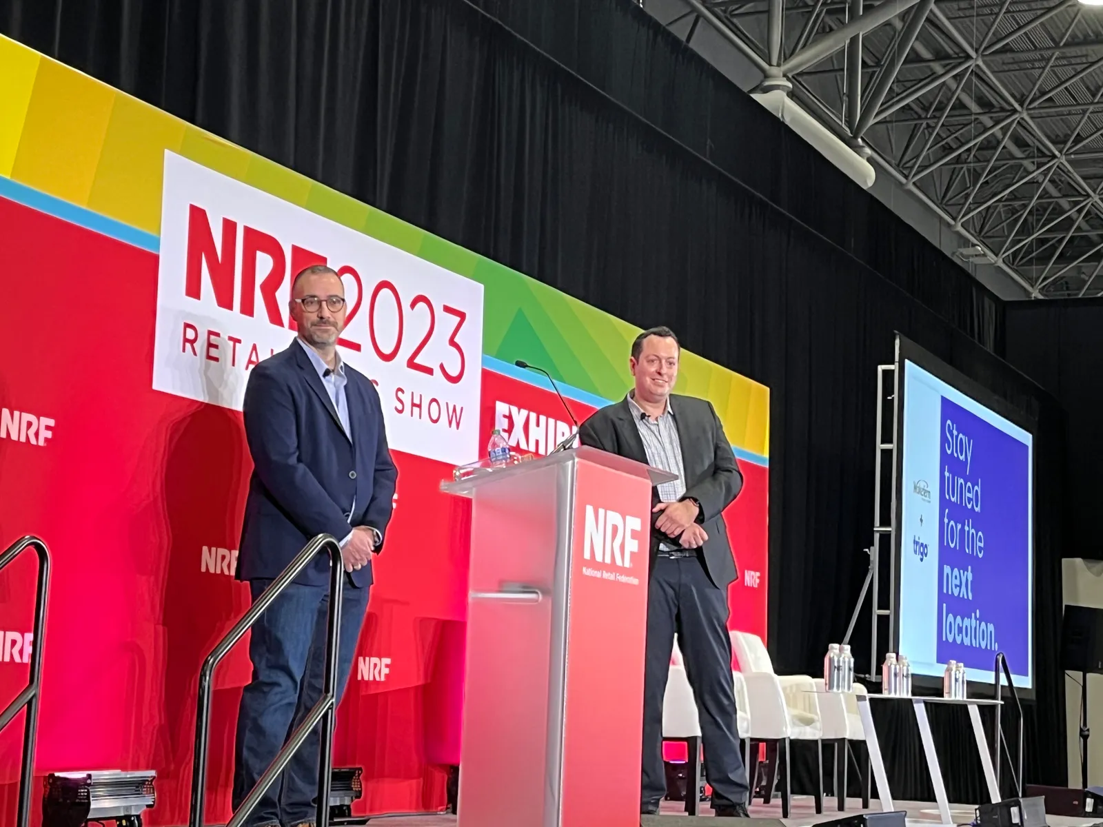 Two people in professional attire on a conference stage.