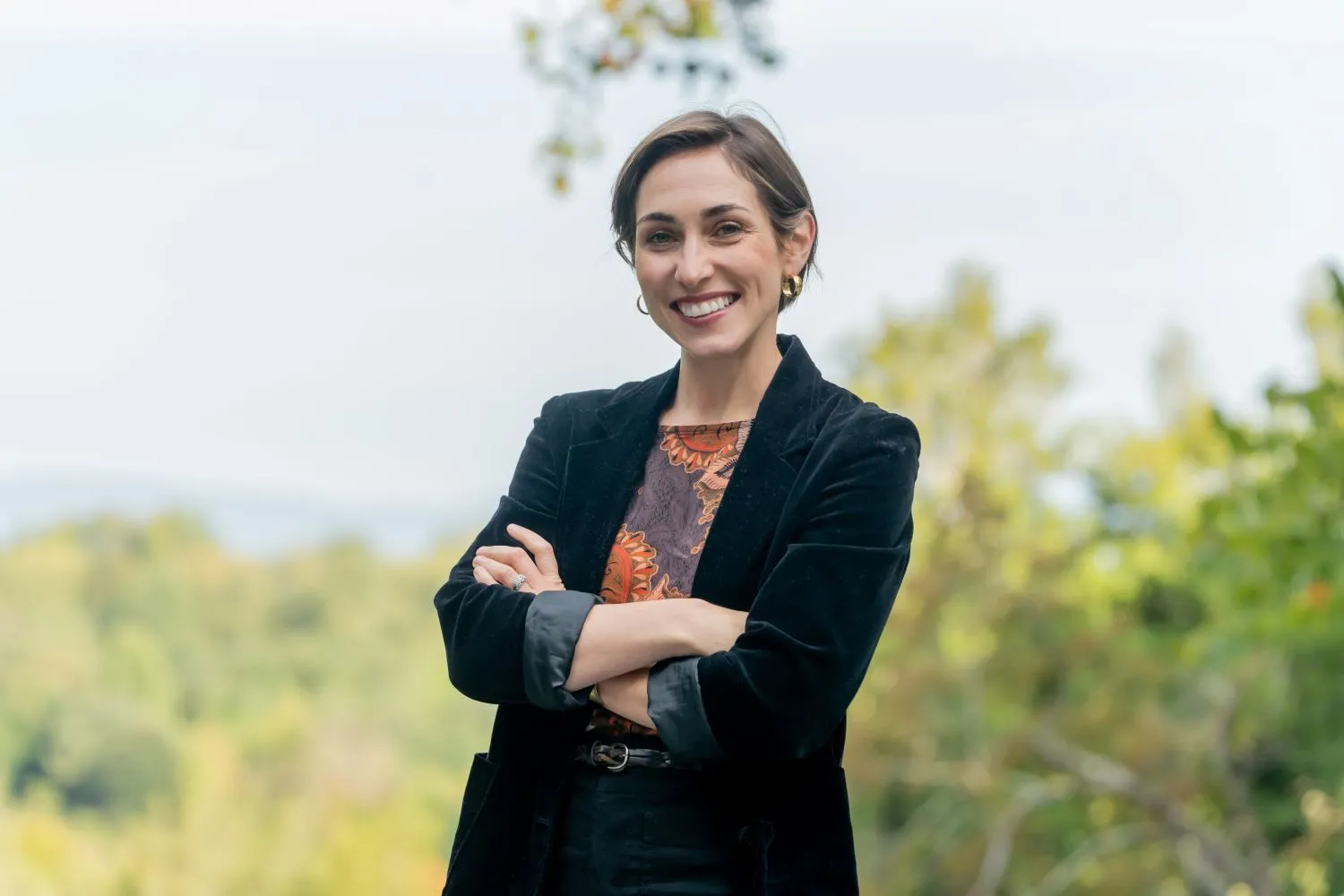 A person in a black blazer smiling at the camera