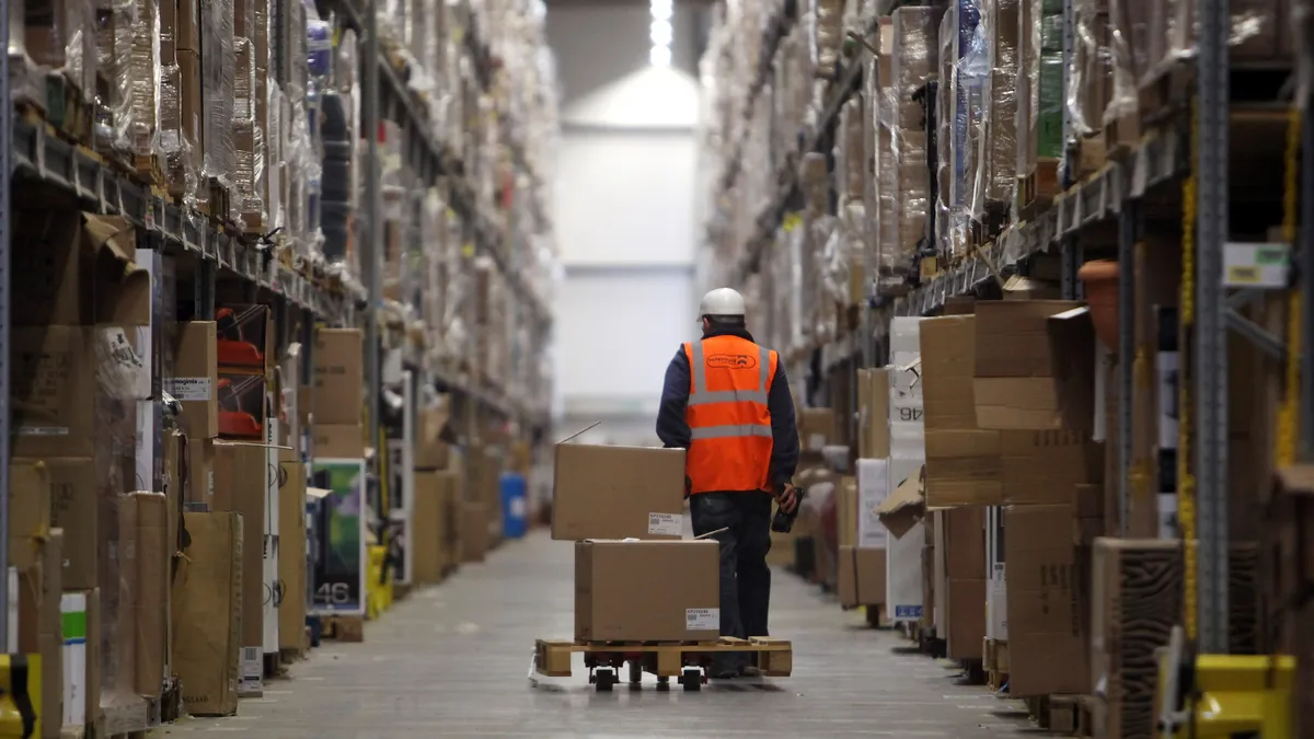 Person pulling a pallet of boxes in a warehouse