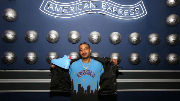 Man sits in front of an Amex logo sign