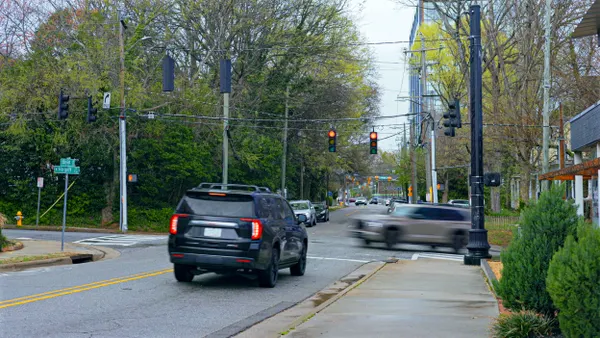 View of intersection showing a red light and a stopped SUV.