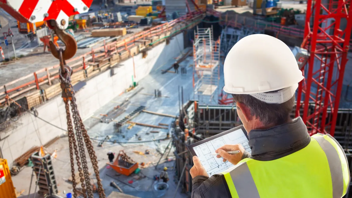 An engineer looks at a table while overseeing a construction site.