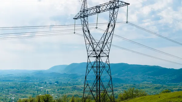 High-voltage electric transmission lines crossing a green field.