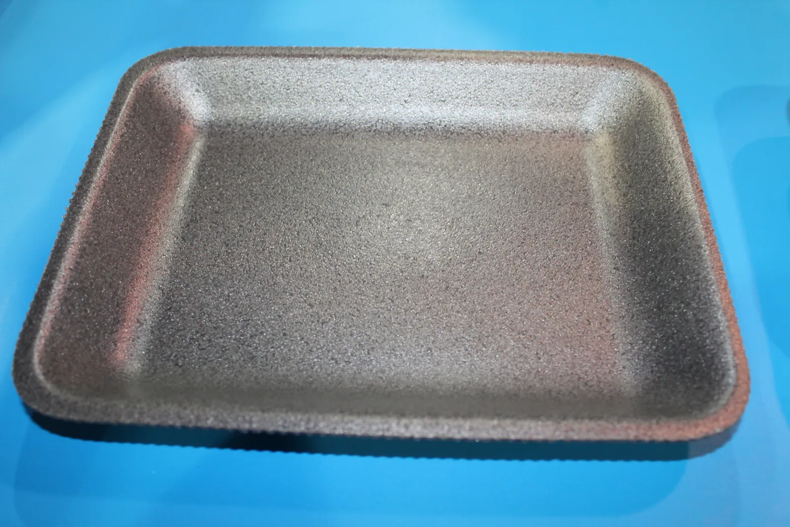 A black foam tray for holding food.