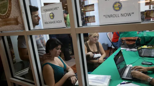 picture of a window inside a room where people sit at tables to enroll in healthcare insurance