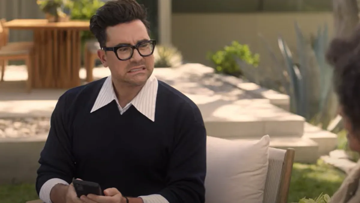 Dan Levy is seen on his phone outdoors in an ad for Norton.