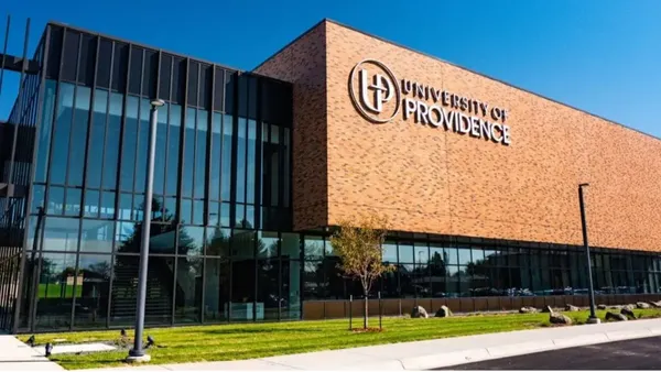 A brick rectangular building with glass lobby on a clear day.
