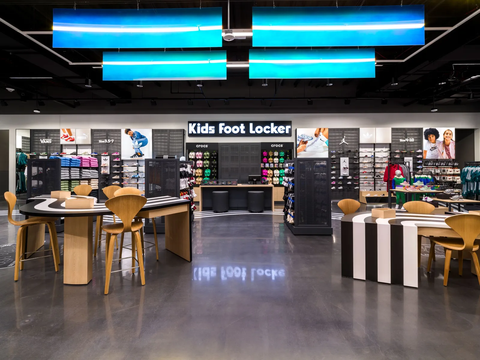 Black and white tables with light wood chairs sit in the center of a store.