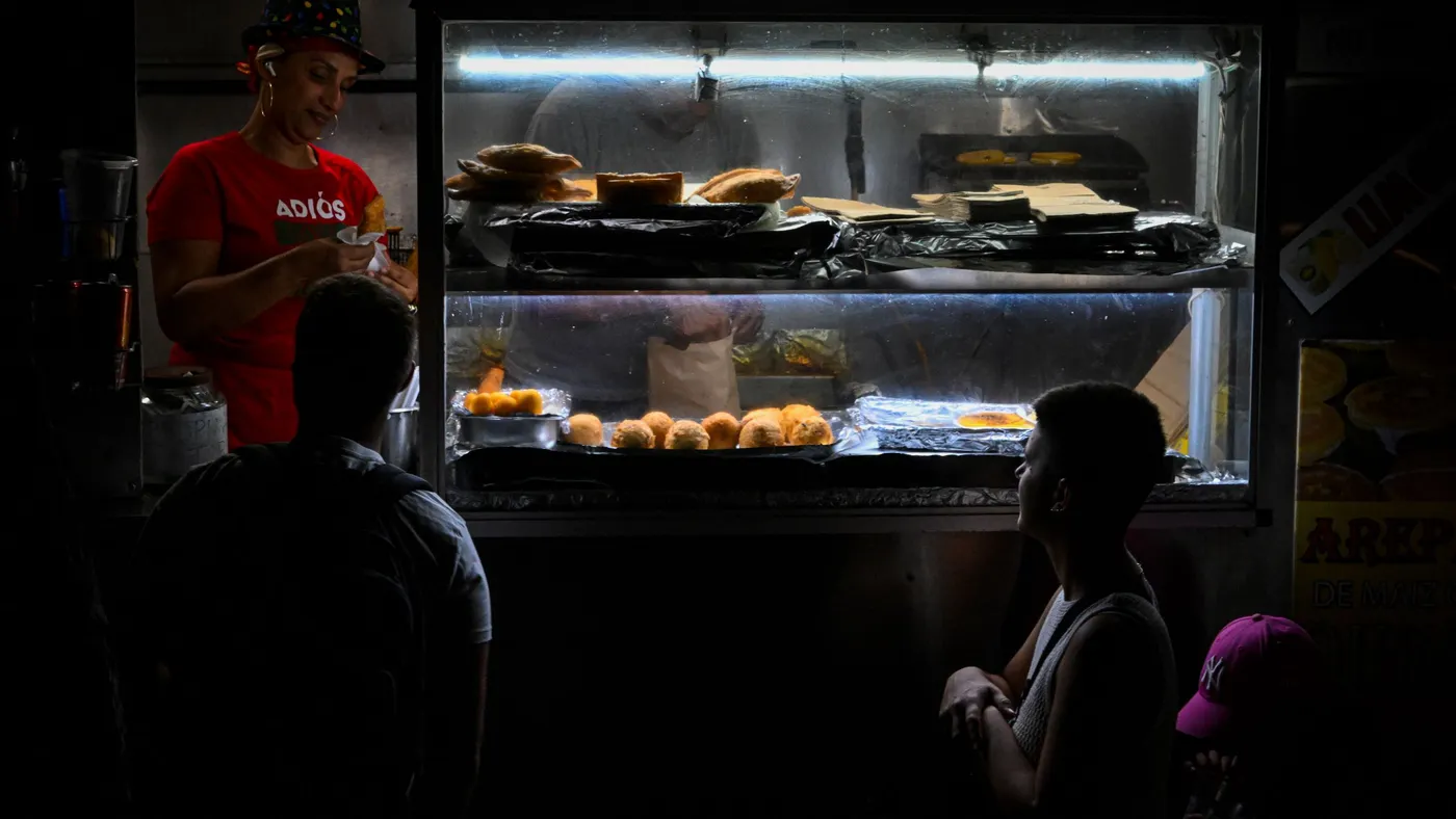 People wait in line for food on a dark street