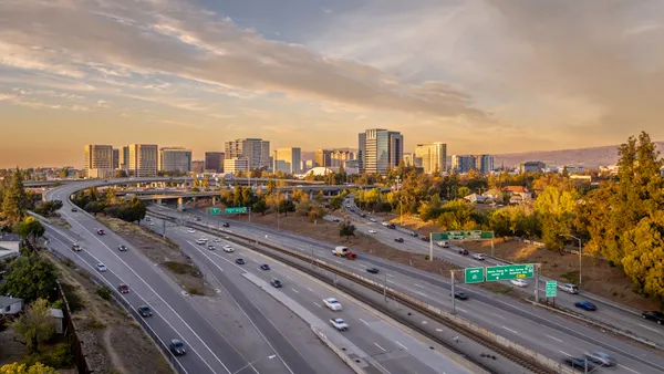 An aerial view of a highway with skyscrapers in the distance.