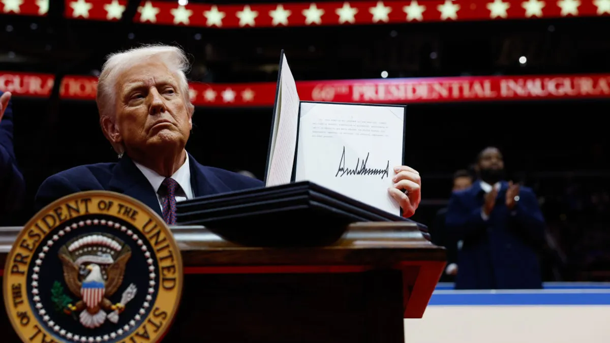 Trump holds up an executive order after signing it on at a post-inauguration parade in Capital One Arena