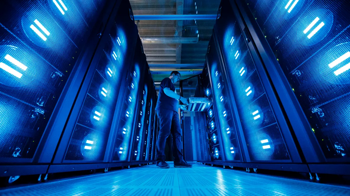 An man stands in front computer and storage systems.