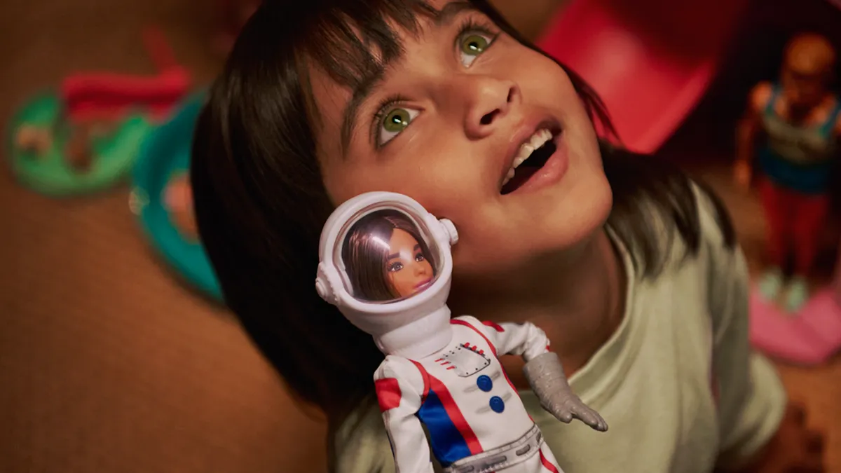 A child and a Barbie astronaut are seen looking up at the sky together for Barbie's "Give Limitless Possibilities" campaign.