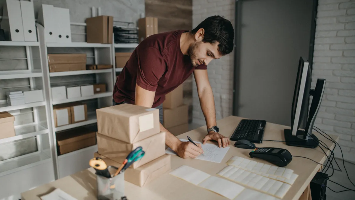 Delivery person preparing bar codes for packages and checking to do list