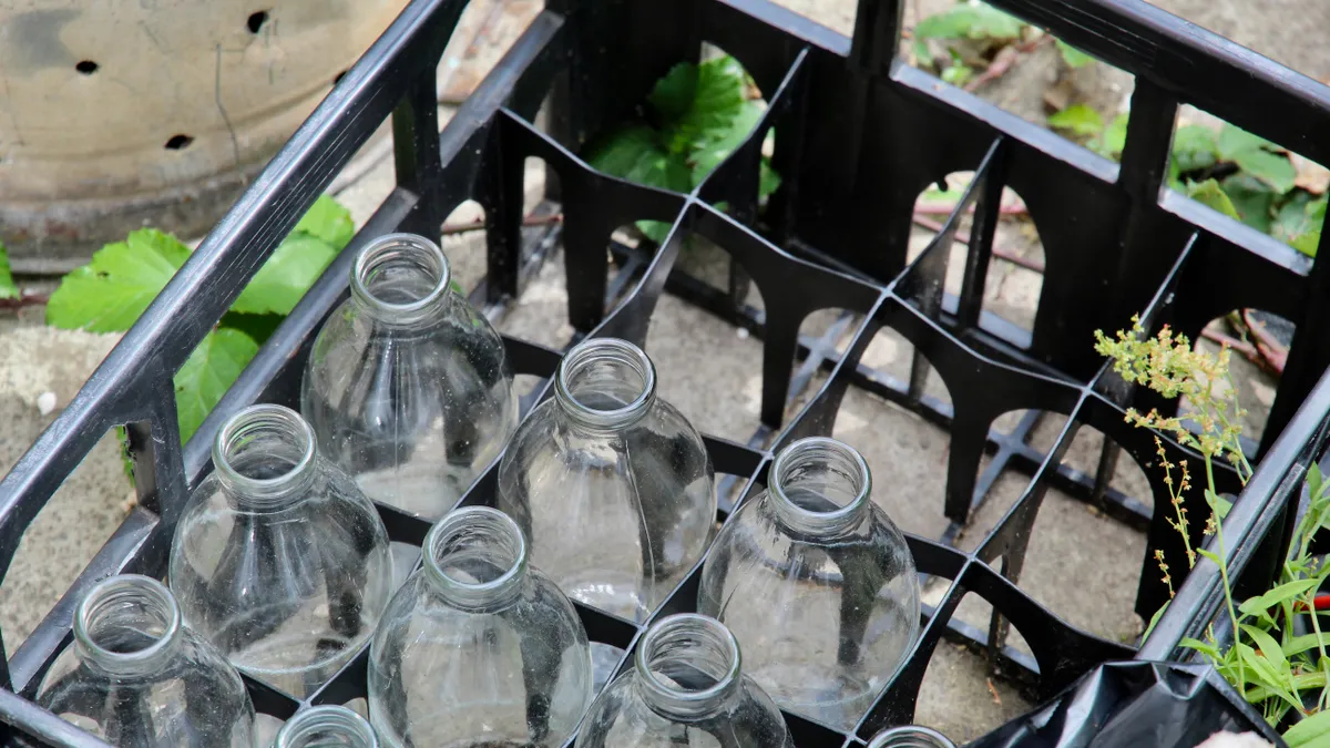 A black crate with empty and clean glass milk bottles