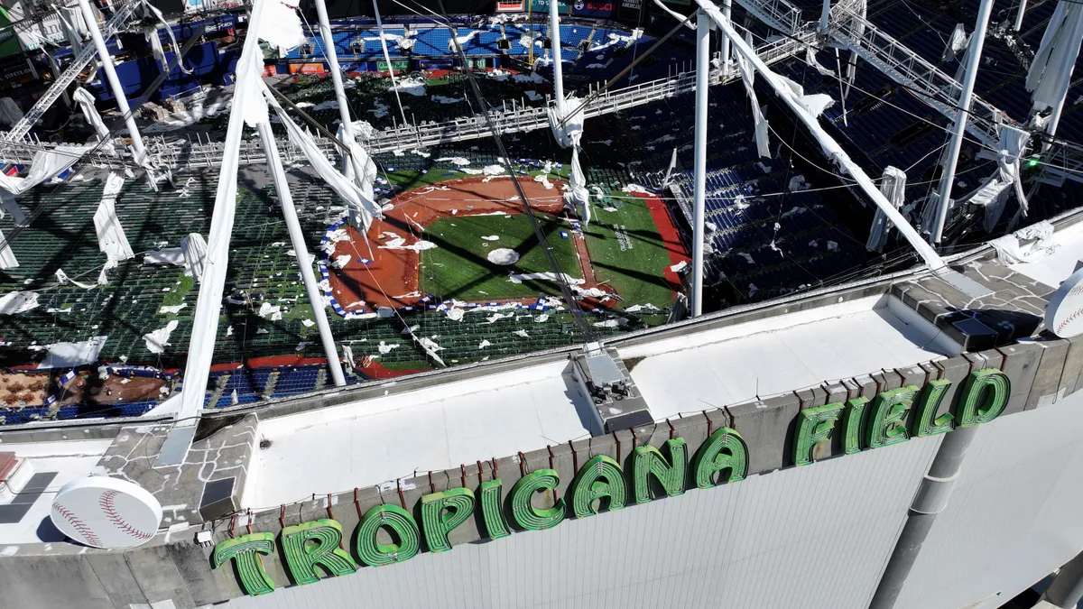 An aerial view of a baseball stadium with a damaged roof.