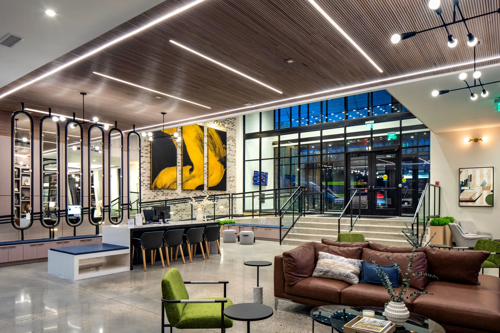 A lobby with many tables, chairs and a row of mirrors.