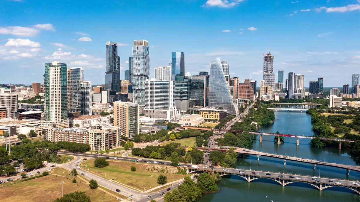 A skyline shot of a city during the day with a river in the foreground.