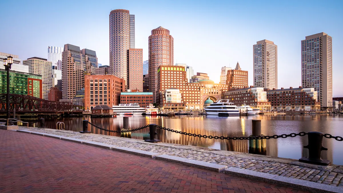 The financial district in Boston, seen against the Boston Harbor at sunrise showcasing a mix of contemporary and historic buildings.