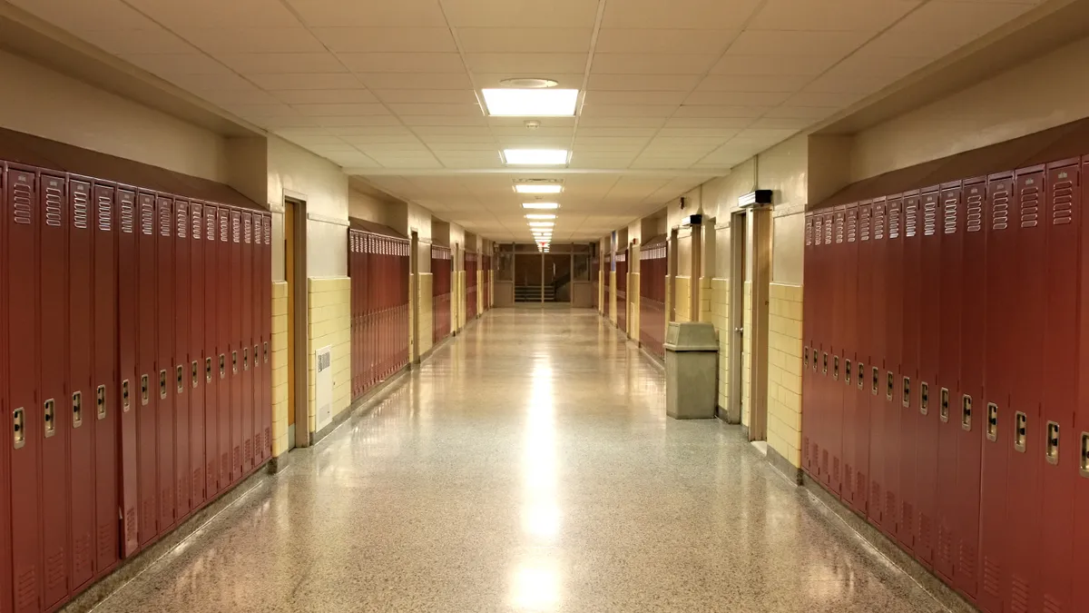 An empty school hallway with rows of lockers on each side.