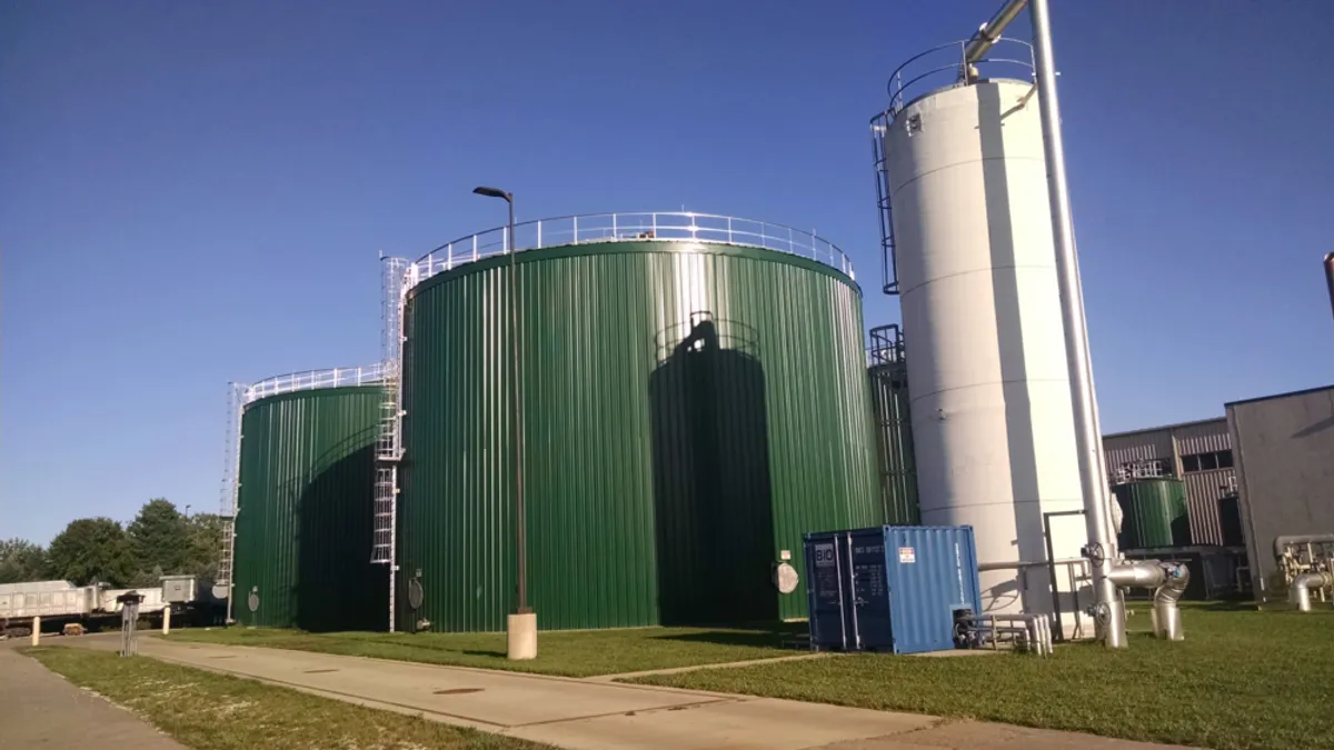 Two multi-story, wide tanks next to a thinner apparatus on an industrial site.