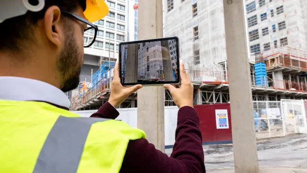A construction worker uses a tablet to capture images on a jobsite.