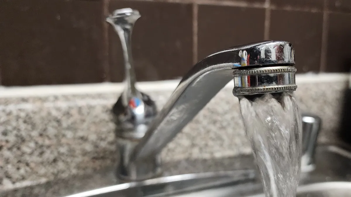 A close-up shot of water running from a kitchen faucet.