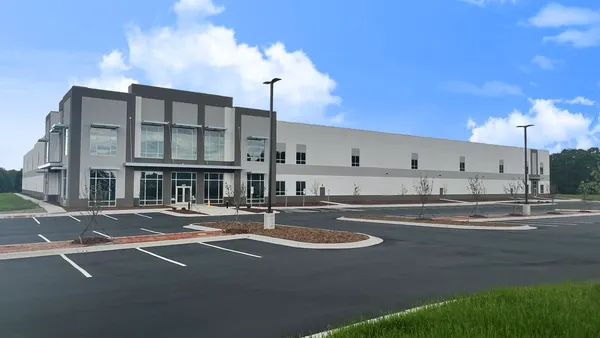 A gray building with an empty parking lot in front of it.