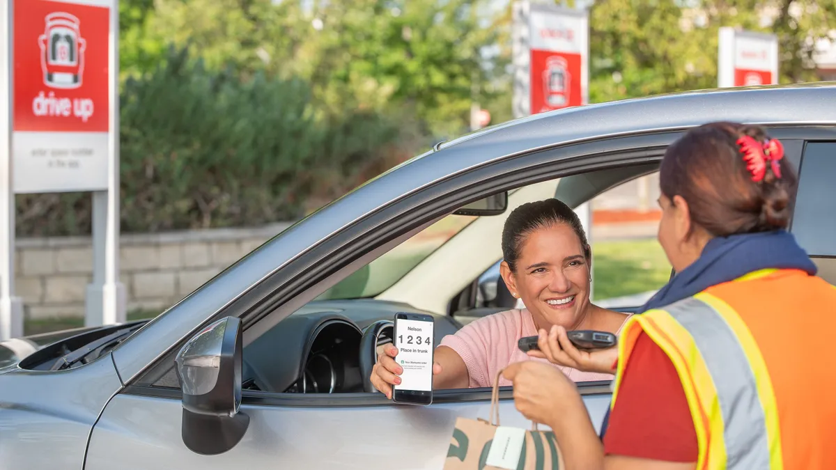 A person in a car accepts a curbside Starbucks order at Target