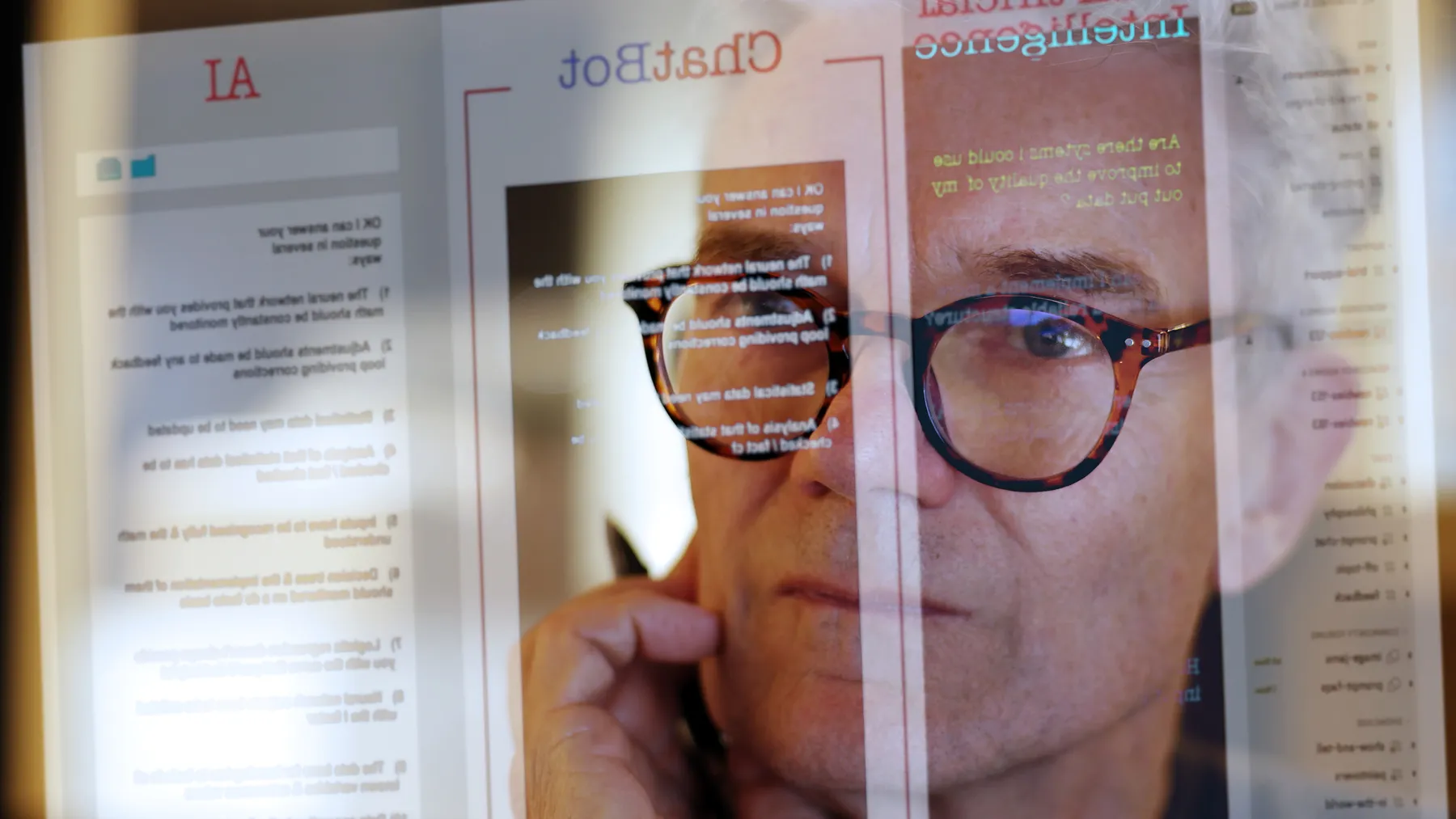 Close up image of a man studying a see-through computer monitor that’s displaying text provided by an chatbot.