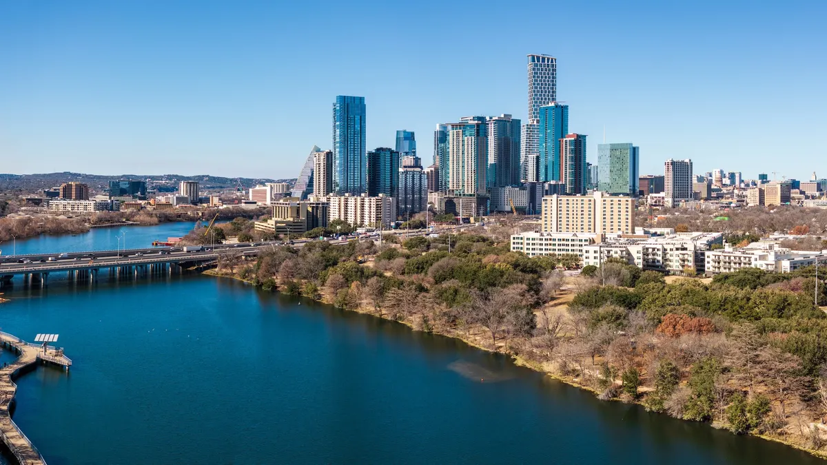 Bridge over blue body of water with city skyline in background.