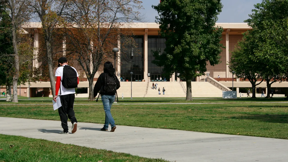 Students walking to class on CSUN campus with academic building in background.