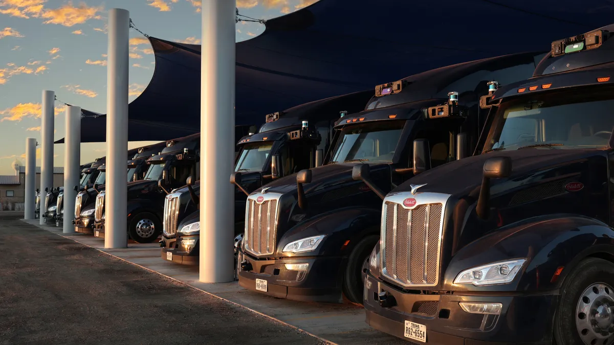 Aurora Innovation self-driving trucks parked in a terminal.