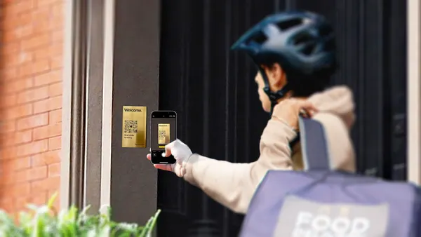 A person holds their phone in front of a metal plaque with a QR code on it.