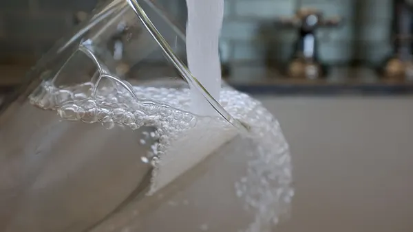 Water runs from a kitchen faucet into a clear cup