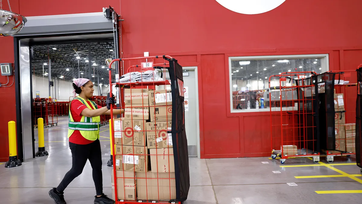 An employee moves a cart of packages at a Target sortation center.