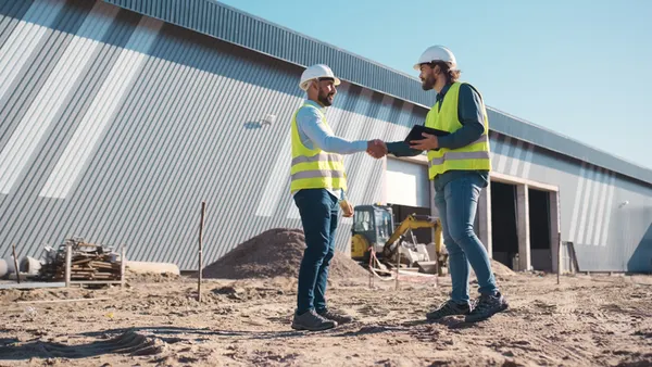 Two construction workers shake hand on a jobsite.